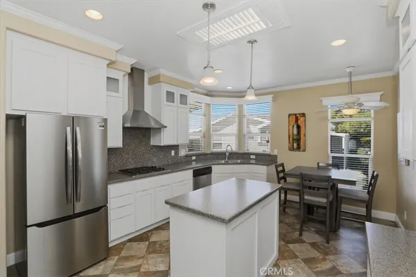 a kitchen with granite countertop a refrigerator a stove a sink a dining table and chairs
