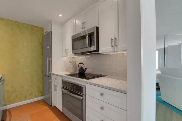 a kitchen with stainless steel appliances granite countertop white cabinets and a stove top oven