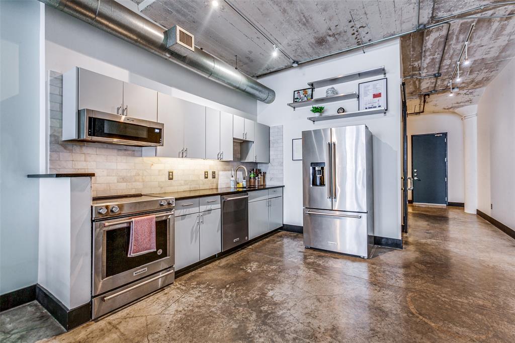 1122 Jackson Street, Unit 917 Dallas, TX 75202 - Photo 6 of 21 a kitchen with stainless steel appliances granite countertop a refrigerator a stove a microwave oven a sink dishwasher and a refrigerator with wooden floor
