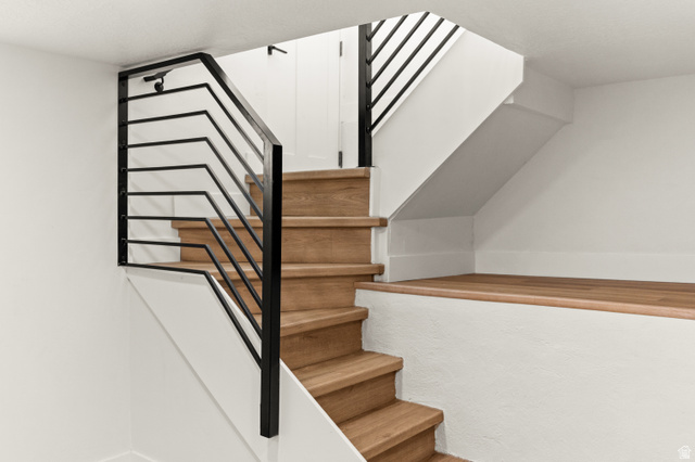 189 West Center Street Midvale, UT 84047 - Photo 28 of 64 Contemporary staircase featuring wood-finish treads, black metal railings, and white painted walls