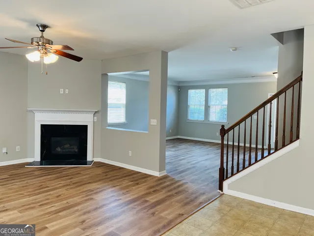 a view of an empty room with wooden floor fireplace and a window
