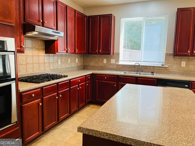 a kitchen with stainless steel appliances granite countertop a sink stove and cabinets