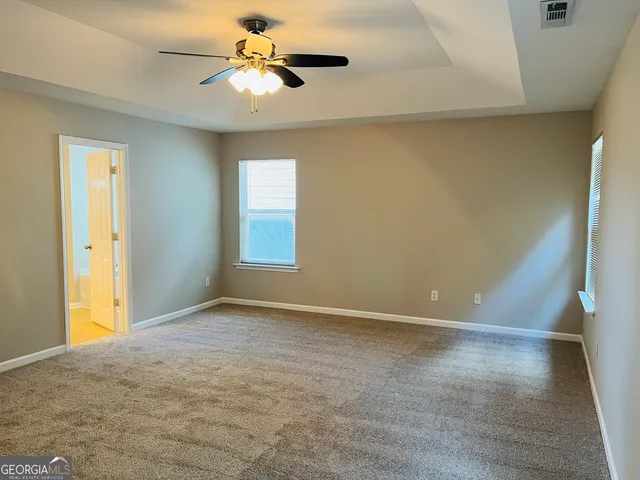 a view of an empty room with window and chandelier fan