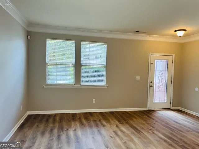 an empty room with wooden floor and windows