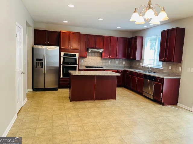 a kitchen with stainless steel appliances granite countertop a stove sink refrigerator and cabinets