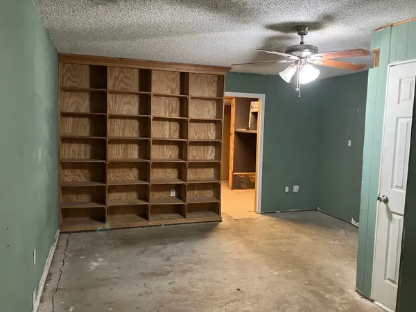 a view of an empty room with a cabinet and a large window