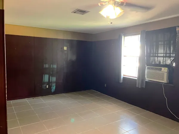 a view of an empty room with window and chandelier fan