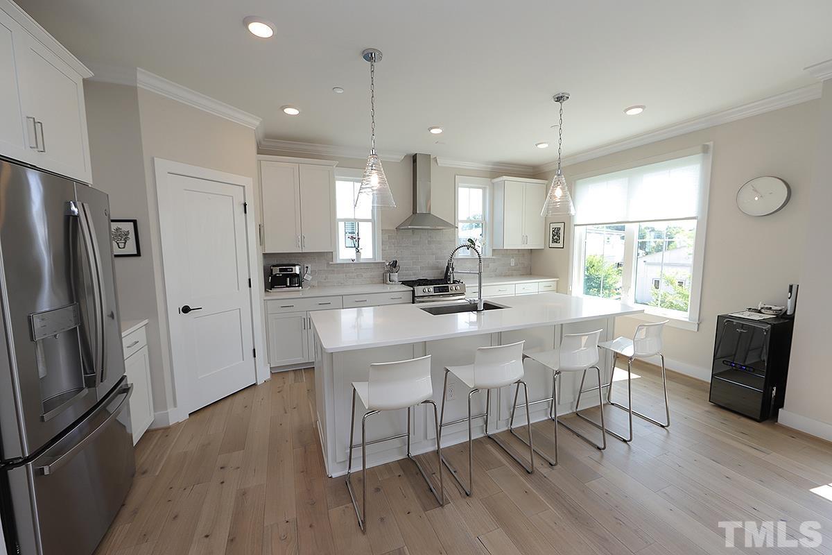 1611 Draper View Loop, Unit 101 Raleigh, NC 27608 - Photo 4 of 13 a kitchen with stainless steel appliances granite countertop a stove a refrigerator a sink a dining table and chairs with wooden floor