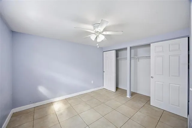 an empty room with a ceiling fan and window