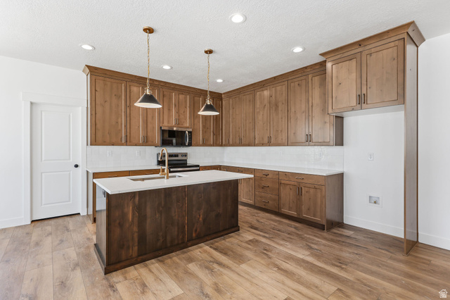 1144 South 4475 West West Point, UT 84015 - Photo 8 of 30 Kitchen featuring wood-finish flooring and a central island with a built-in sink and gold-tone faucet