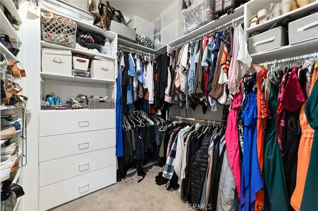 a view of walk in closet with clothes and shoes
