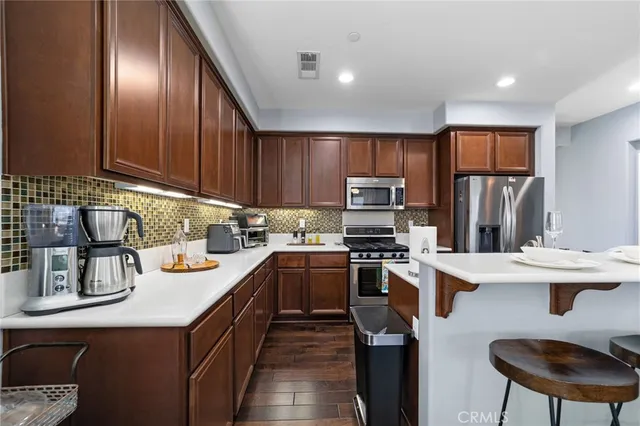 a kitchen with stainless steel appliances granite countertop a sink stove refrigerator and cabinets