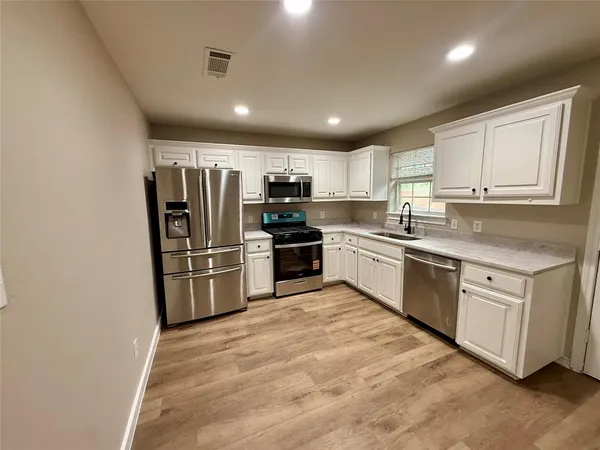 a kitchen with granite countertop a refrigerator sink and cabinets