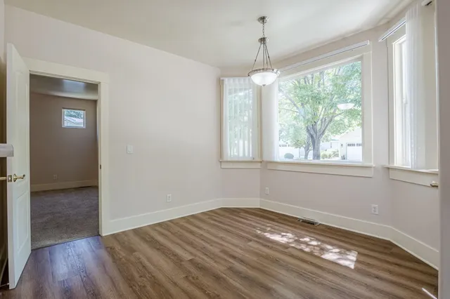a view of empty room with wooden floor and fan