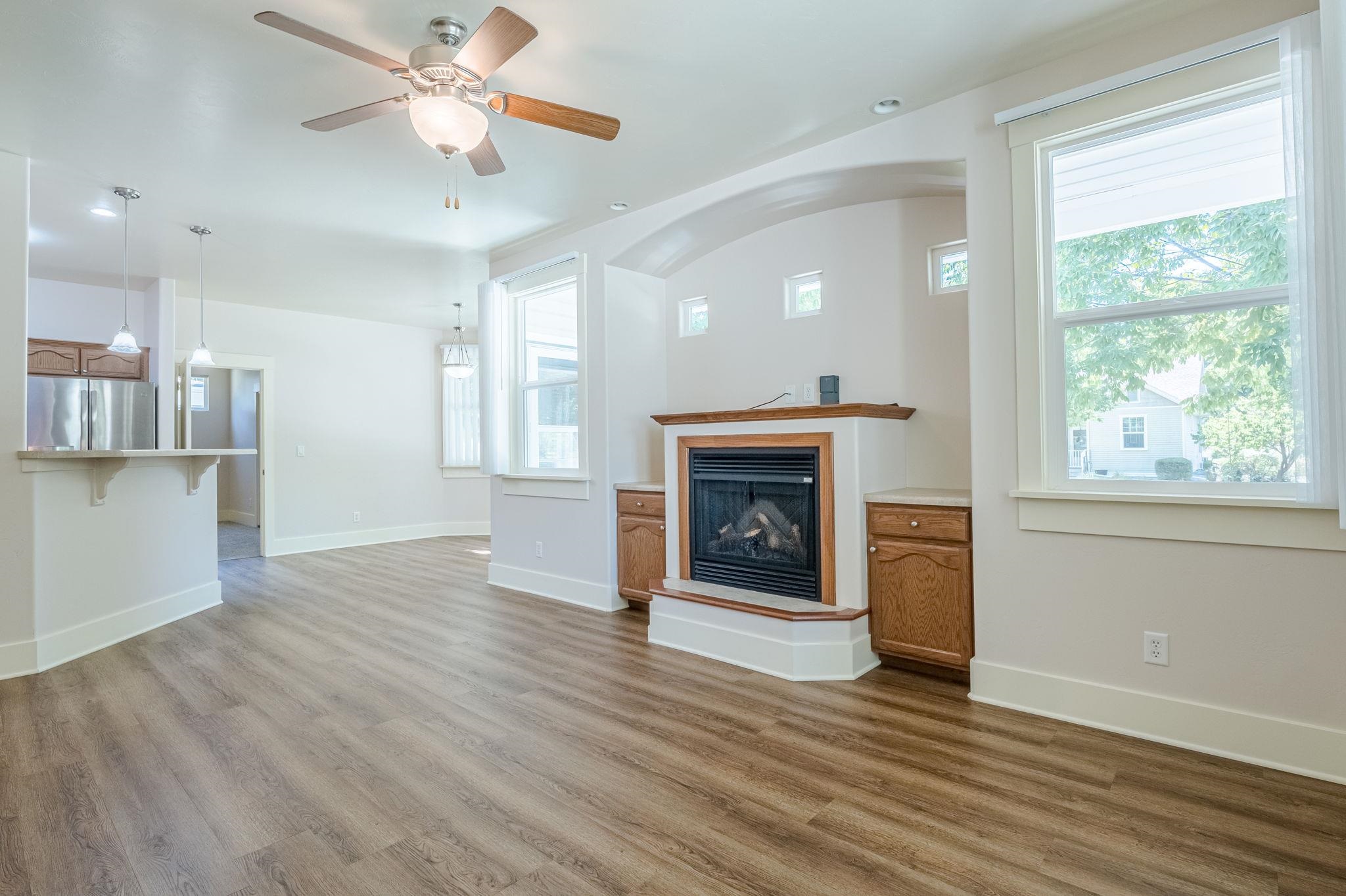 812 Alyssum Court Fruita, CO 81521 - Photo 9 of 41 an empty room with wooden floor a fireplace a kitchen view and a window