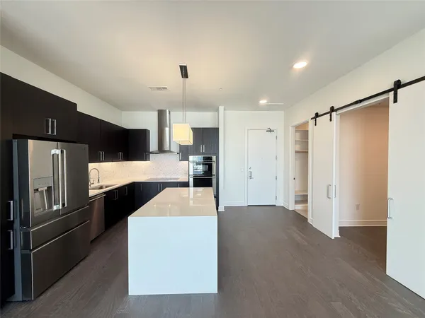 a kitchen with stainless steel appliances kitchen island a refrigerator sink and cabinets