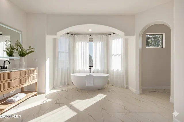 a bathroom with a tub a sink and a large mirror