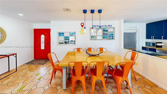 a kitchen with stainless steel appliances kitchen island granite countertop a refrigerator a sink dishwasher a dining table and chairs with wooden floor