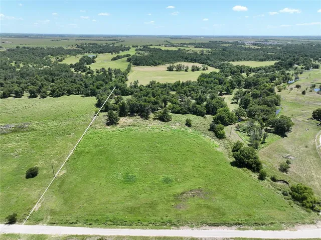 an aerial view of residential houses with outdoor space and trees