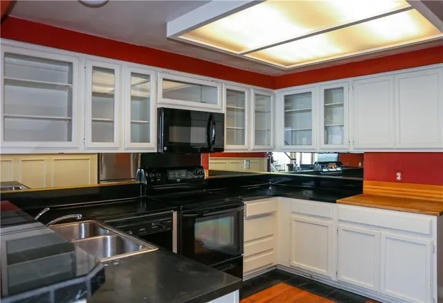 a kitchen with granite countertop a stove and white cabinets