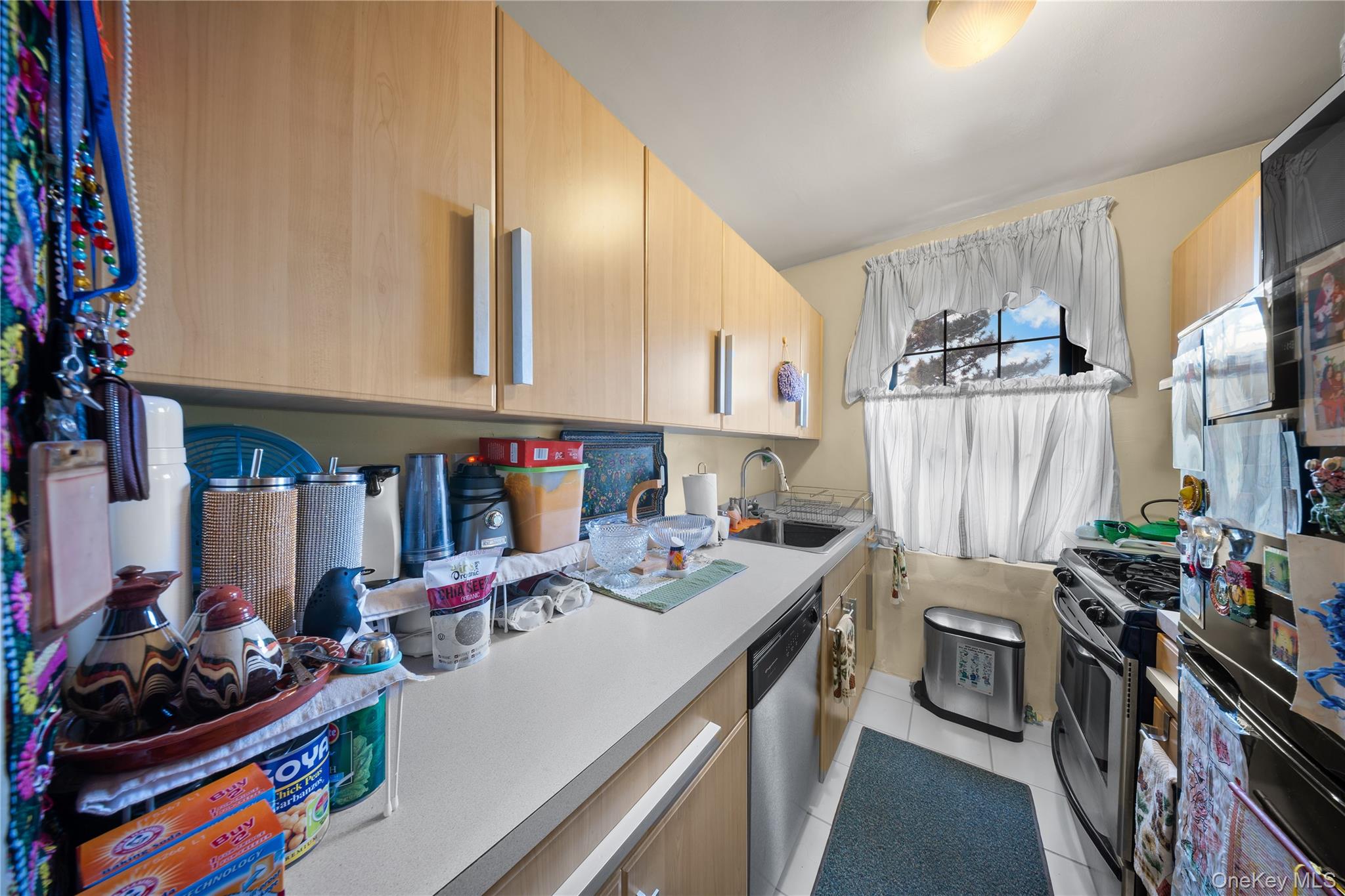 70-79 Park Drive East, Unit B Queens, NY 11367 - Photo 7 of 25 Kitchen with appliances with stainless steel finishes, light tile patterned floors, light countertops, and light brown cabinets