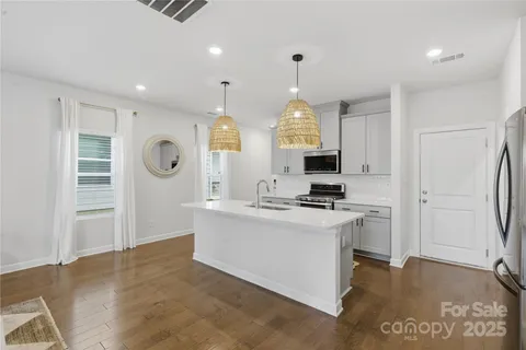 a view of a kitchen with kitchen island a sink stainless steel appliances and cabinets