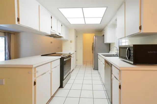 a kitchen with granite countertop a stove a sink and a refrigerator