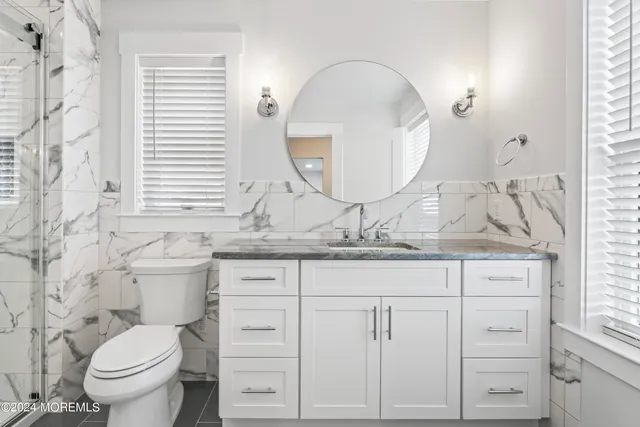 a bathroom with a granite countertop toilet a sink and a mirror