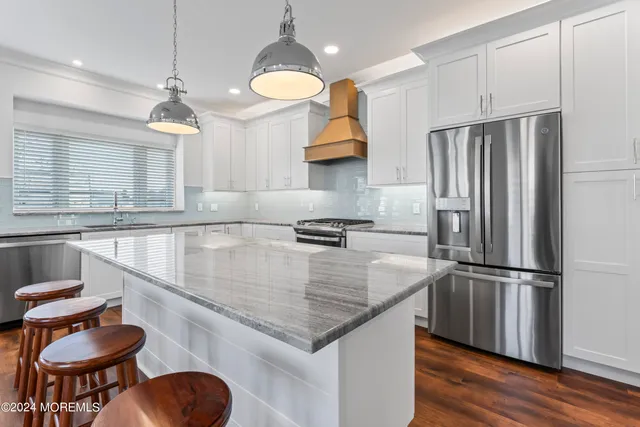 a kitchen with stainless steel appliances granite countertop a sink a stove and a refrigerator