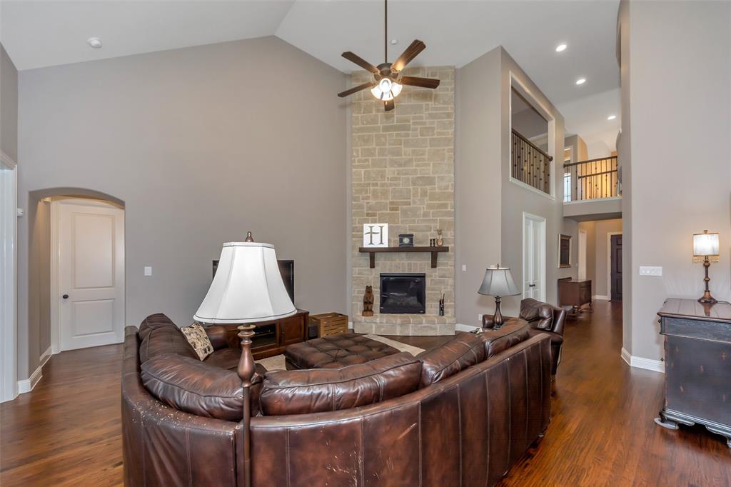 1001 West Bluff Way Roanoke, TX 76262 - Photo 17 of 40 Living room with high vaulted ceiling, dark wood finished floors, a stone fireplace, a ceiling fan, and arched walkways