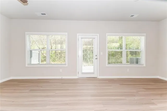 a view of an empty room with wooden floor and windows