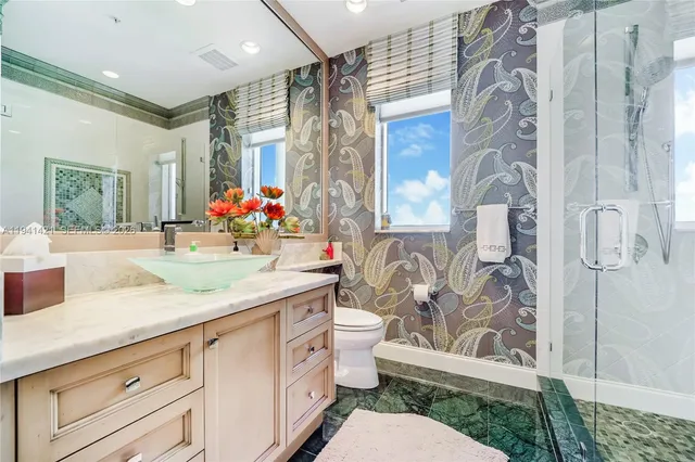 a bathroom with a granite countertop sink mirror vanity and toilet