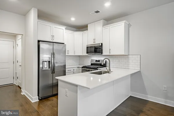 a kitchen with a refrigerator a sink a stove a microwave and wooden floor