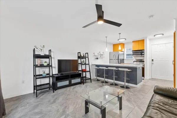 a living room with stainless steel appliances kitchen island granite countertop furniture and a sink