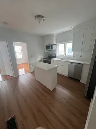 a room with wooden floors and white cabinets