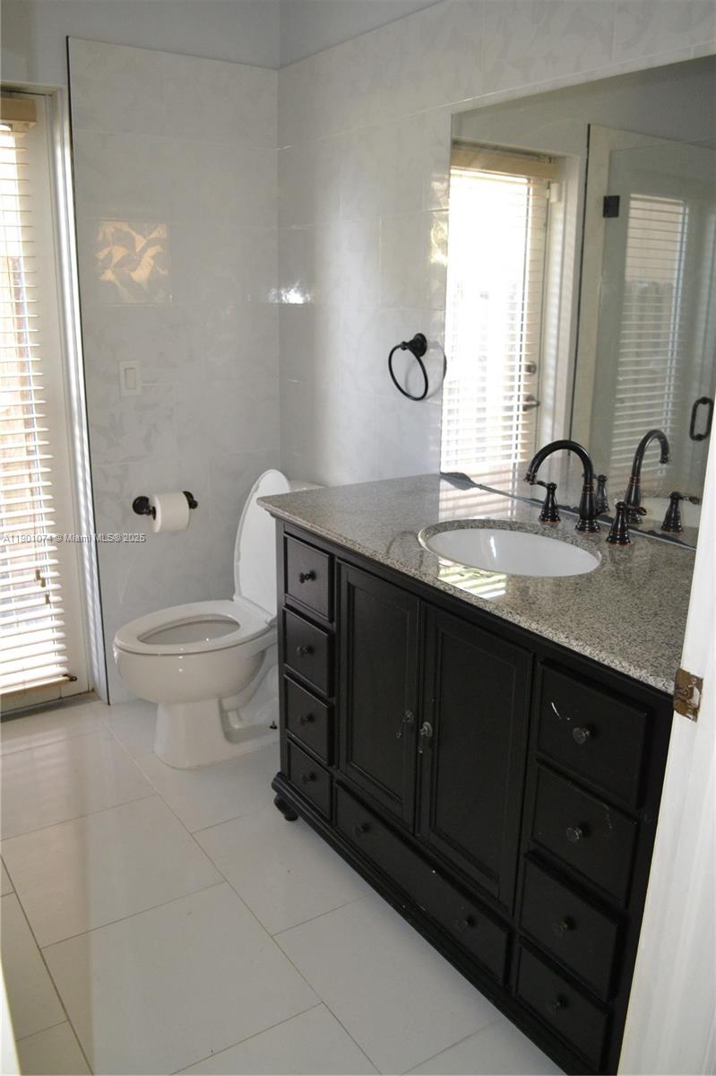 22418 Southwest 94th Path Cutler Bay, FL 33190 - Photo 45 of 71 a bathroom with a granite countertop sink a toilet and a mirror