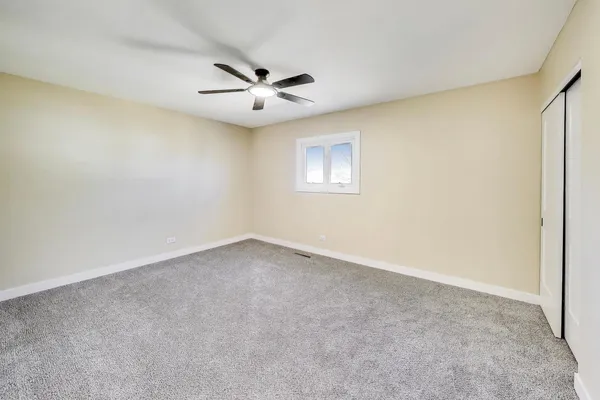 an empty room with a window and a fan