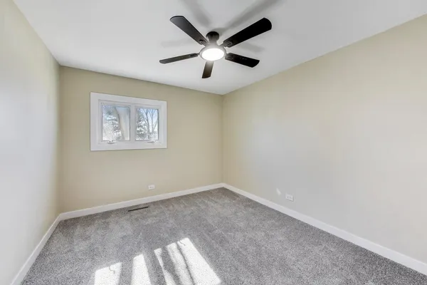 an empty room with windows and ceiling fan