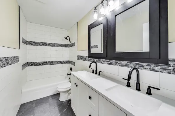 a bathroom with a double vanity sink double mirror bathtub and toilet