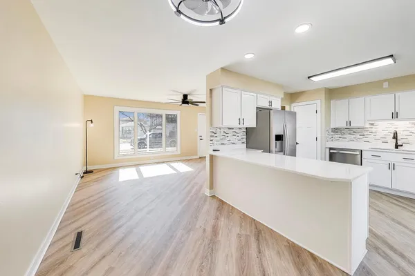 a large white kitchen with wooden floors and white stainless steel appliances