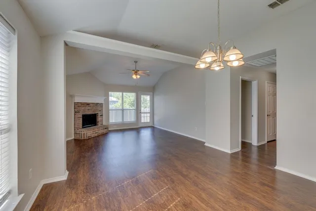 a view of a livingroom with a fireplace wooden floor and chandelier