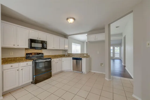 a kitchen with granite countertop white cabinets and stainless steel appliances