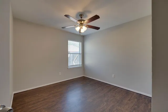 an empty room with wooden floor a ceiling fan and closet area