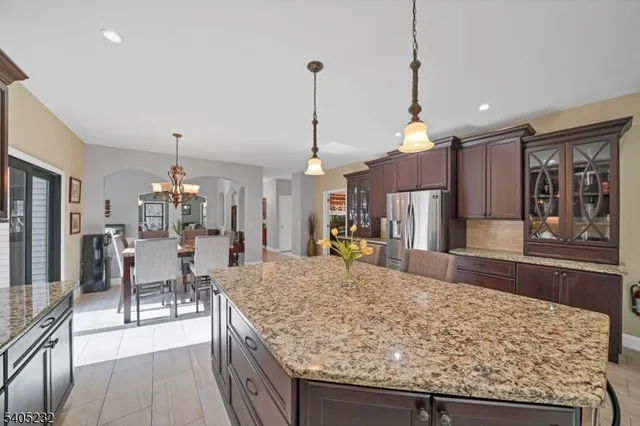 a kitchen with stainless steel appliances granite countertop a sink a stove a refrigerator and a wooden cabinets