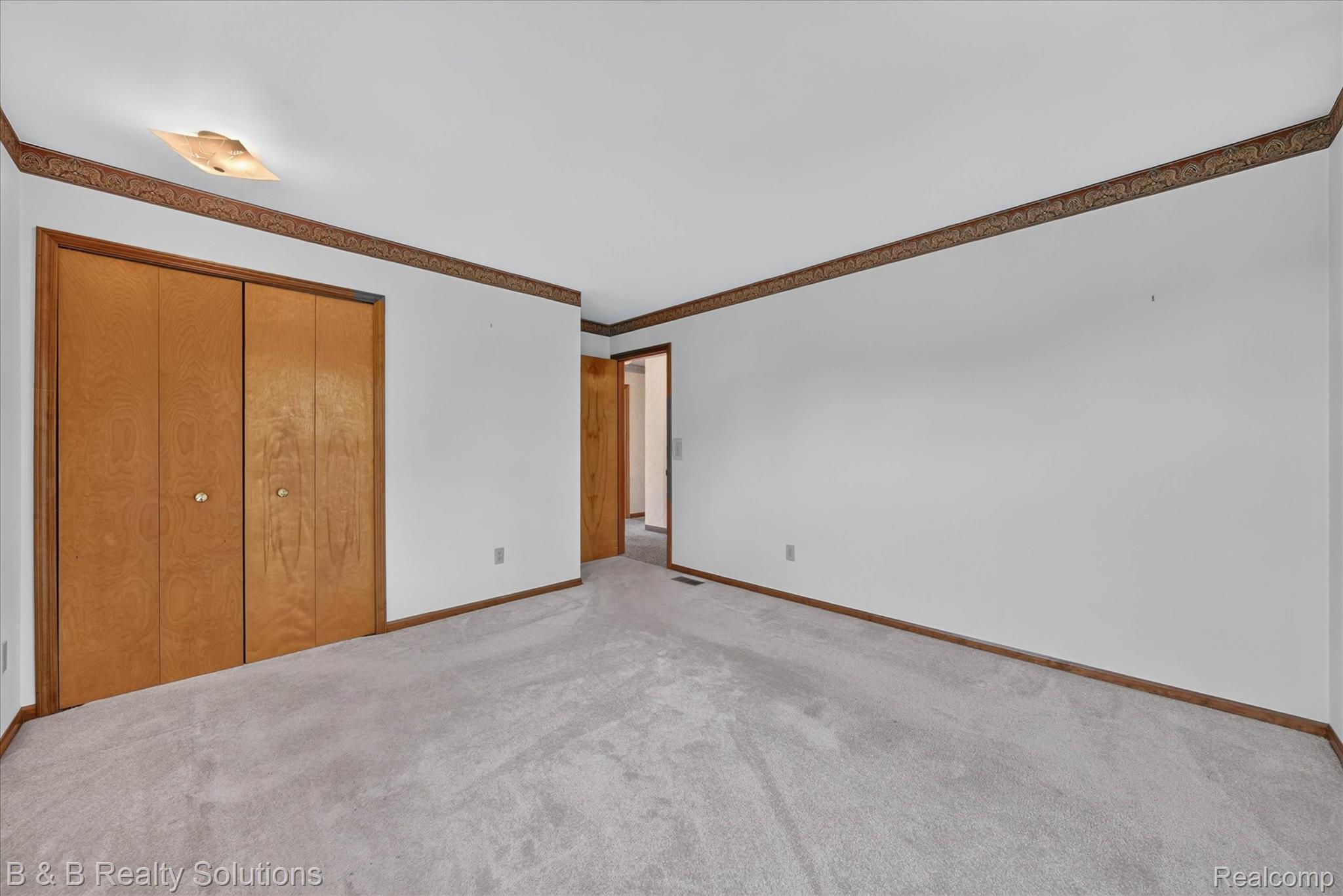 6605 Patrick Road North Branch, MI 48461 - Photo 22 of 44 Spacious bedroom with rich wood-finish closet doors, exposed wood beam ceiling detail, and neutral carpet flooring