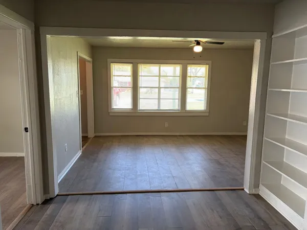 an empty room with wooden floor and windows