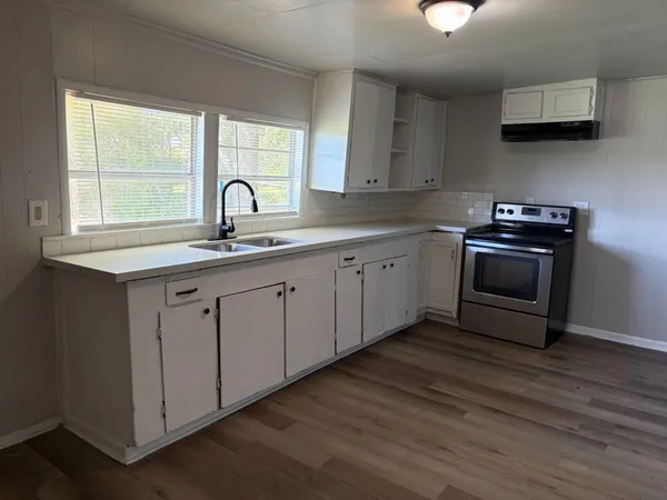 a kitchen with stainless steel appliances granite countertop a sink a stove and a wooden floors