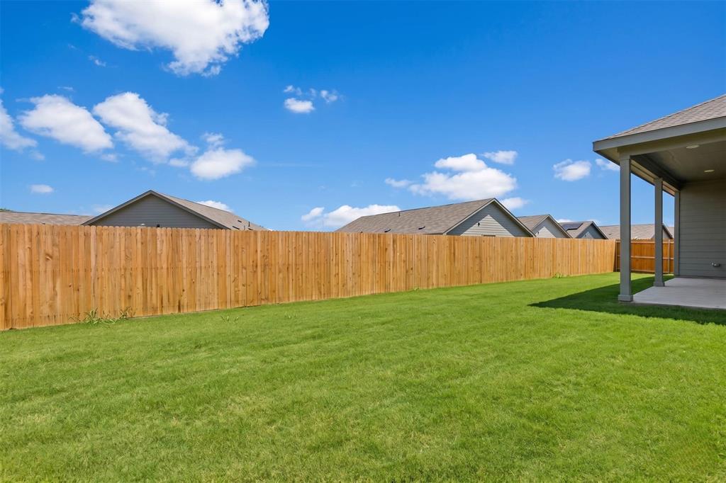 656 Waymaker Way Princeton, TX 75407 - Photo 39 of 40 Expansive green lawn featuring a wooden privacy fence and a covered patio with concrete flooring