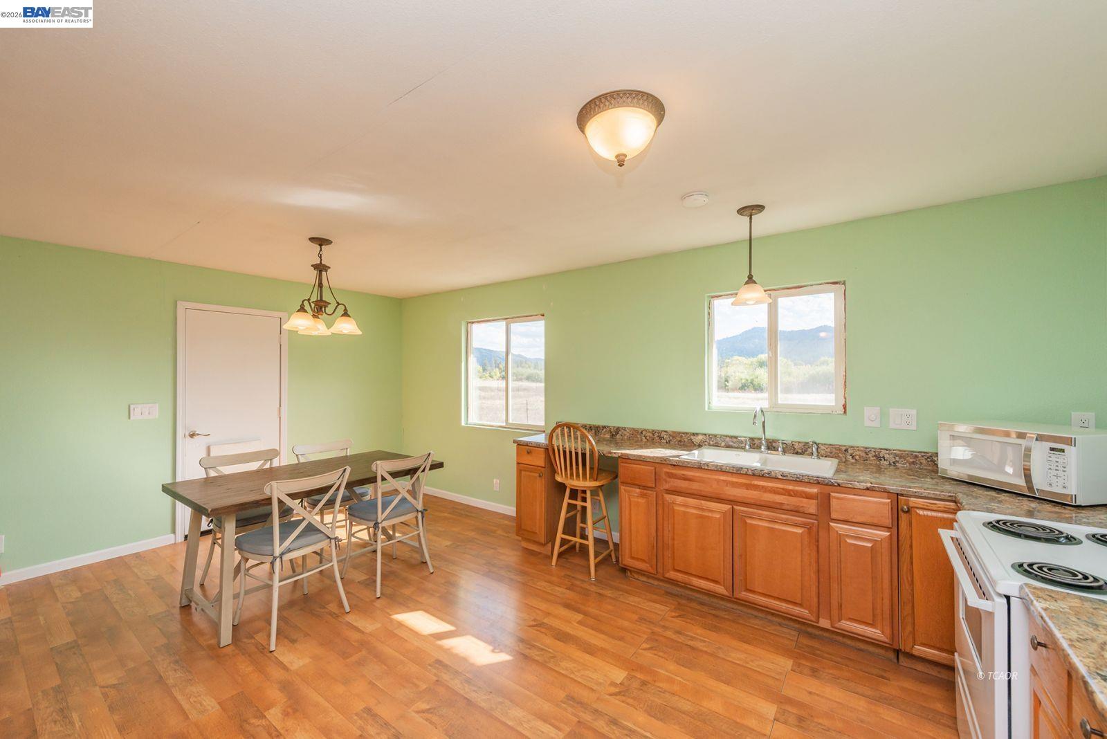 1095 Hyampom Road Hayfork, CA 96041 - Photo 15 of 41 a kitchen with stainless steel appliances granite countertop a table chairs stove and wooden floor