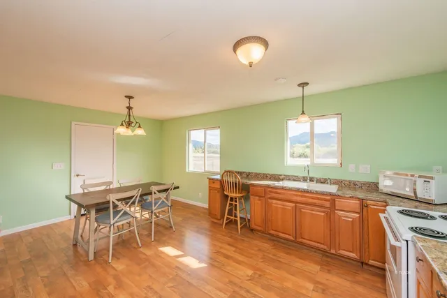 a kitchen with stainless steel appliances granite countertop a table chairs stove and wooden floor